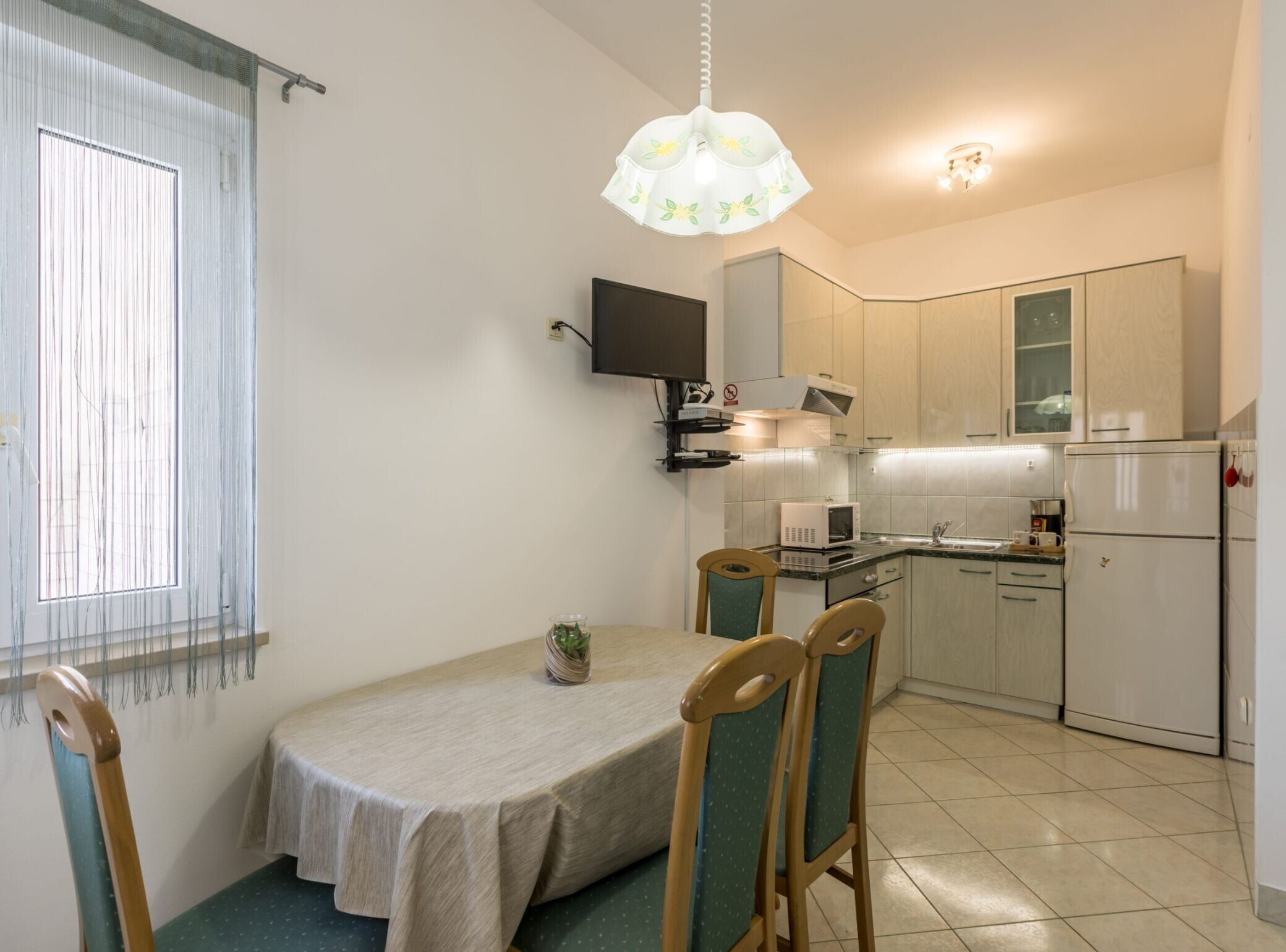 A compact kitchen with a dining table, chairs, a TV, and a microwave.