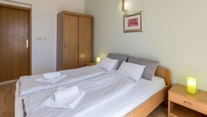 A neatly made bed with white linens and towels, a wooden wardrobe, a bedside table with a lamp, and a framed picture on the wall. - Adriatic Island Sea View -Cmfrt 1Bedroom/TerraceA2 (Bol)