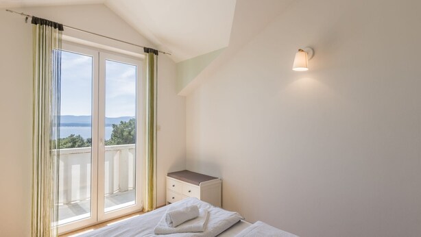 A bedroom with a bed, a nightstand, a window with curtains, and a view of the sea. - Adriatic Island Sea View -Cmfrt 1Bedroom/TerraceA2 (Bol)