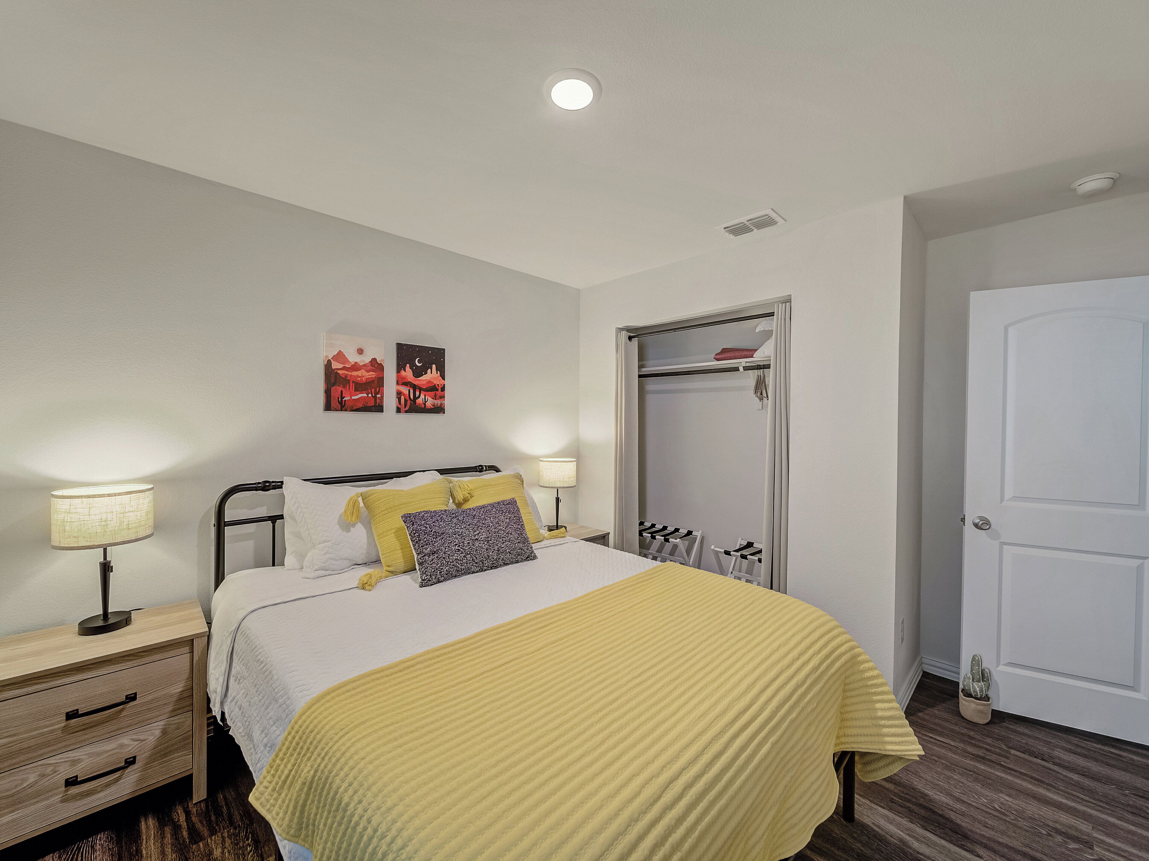 A bedroom with a bed, bedside tables, a wardrobe, and a door.