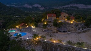 A resort with a swimming pool, stone structures, and a view of the surrounding landscape.