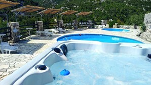 A hot tub with a stone patio and outdoor seating.