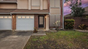 A two-story house with a garage, a front door, and a small garden area. - Cowboy Oasis !King Bed with WiFi by Domain (Austin)
