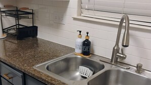 A kitchen with granite countertops, stainless steel sink, and modern cabinetry. - Cowboy Oasis !King Bed with WiFi by Domain (Austin)