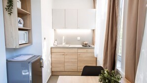 A compact kitchen with a wooden countertop, a sink, and cabinets. There is a dining table with chairs and a potted plant. - Stylish Apartments with Osijek - Standard Studio (Osijek)