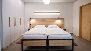 A modern bedroom with a double bed, bedside lamps, a wooden headboard, and a wardrobe with vertical handles. - Stylish Apartments with Osijek - Standard Studio (Osijek)