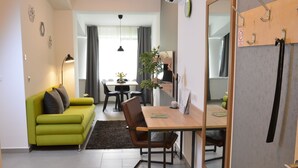 Een moderne woonkamer met een groene bank, een houten eettafel en een spiegel.