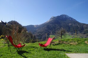 Two red folding chairs in a grassy field with a mountain in the background.