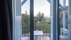 Uma varanda com mesa e cadeiras, com vista para uma paisagem pitoresca com árvores e colinas.