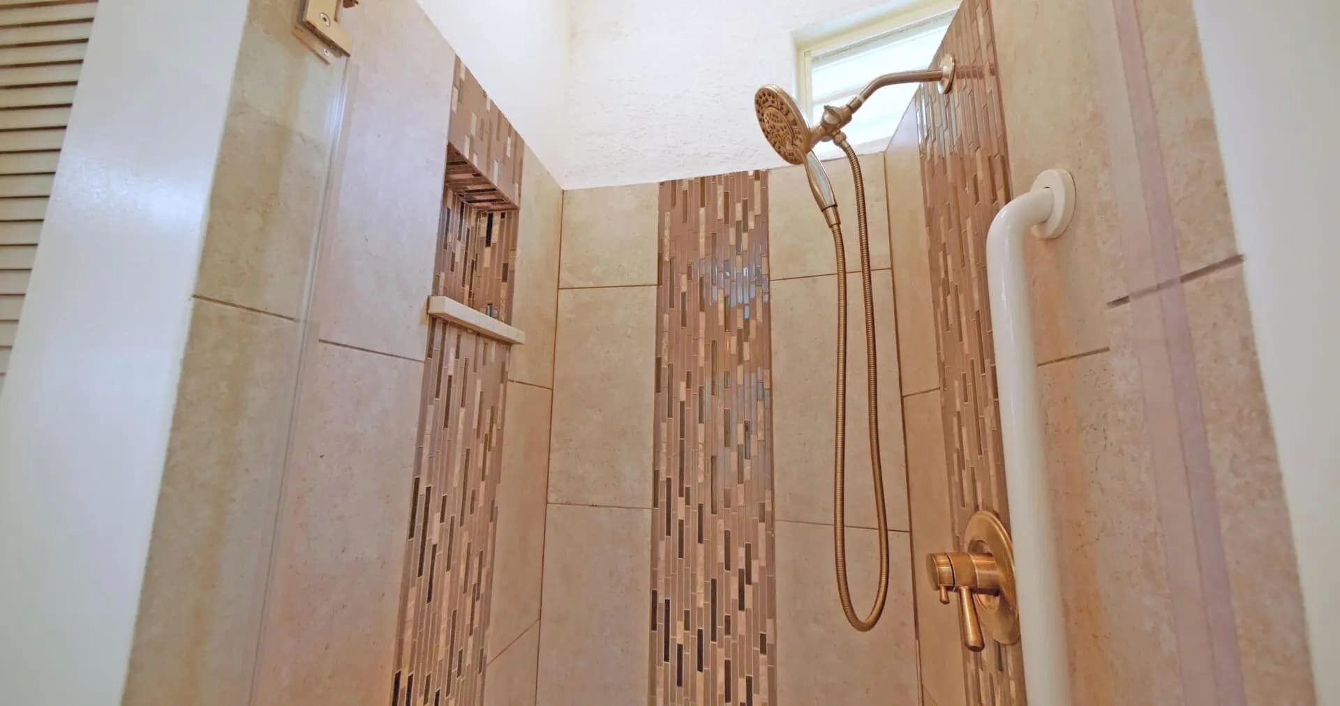 A shower with a modern design, featuring a vertical panel wall and a handheld showerhead.