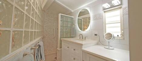 A bathroom with a glass shower enclosure, a vanity with a mirror, and a towel rack.