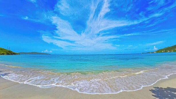 Una playa con agua azul cristalina y una orilla arenosa.