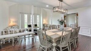 A dining area with a wooden table and chairs, a bench, and a hanging light fixture. - Patio + Pool Table: Lake Marion Getaway (Santee)
