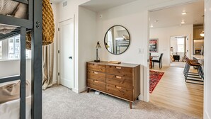 A modern bedroom with a wooden dresser, a round mirror, and a bunk bed with a hanging blanket. - 25 Mi to Zion: Rock 'n' Roll Condo w/ Mtn View! (Hurricane)