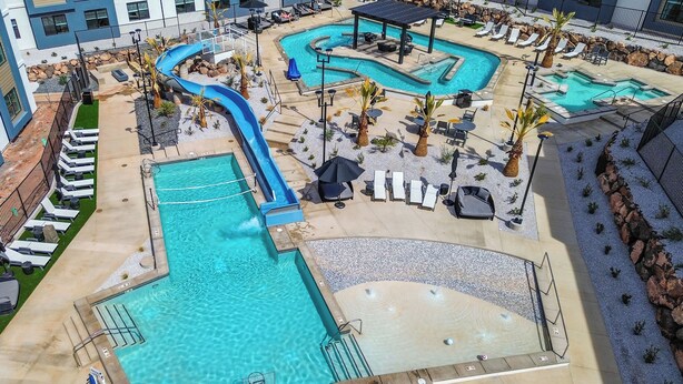 A rooftop pool area with multiple swimming pools, lounge chairs, and a slide. - 25 Mi to Zion: Rock 'n' Roll Condo w/ Mtn View! (Hurricane)