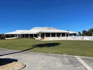 A modern building with a covered patio area and a well-maintained lawn.