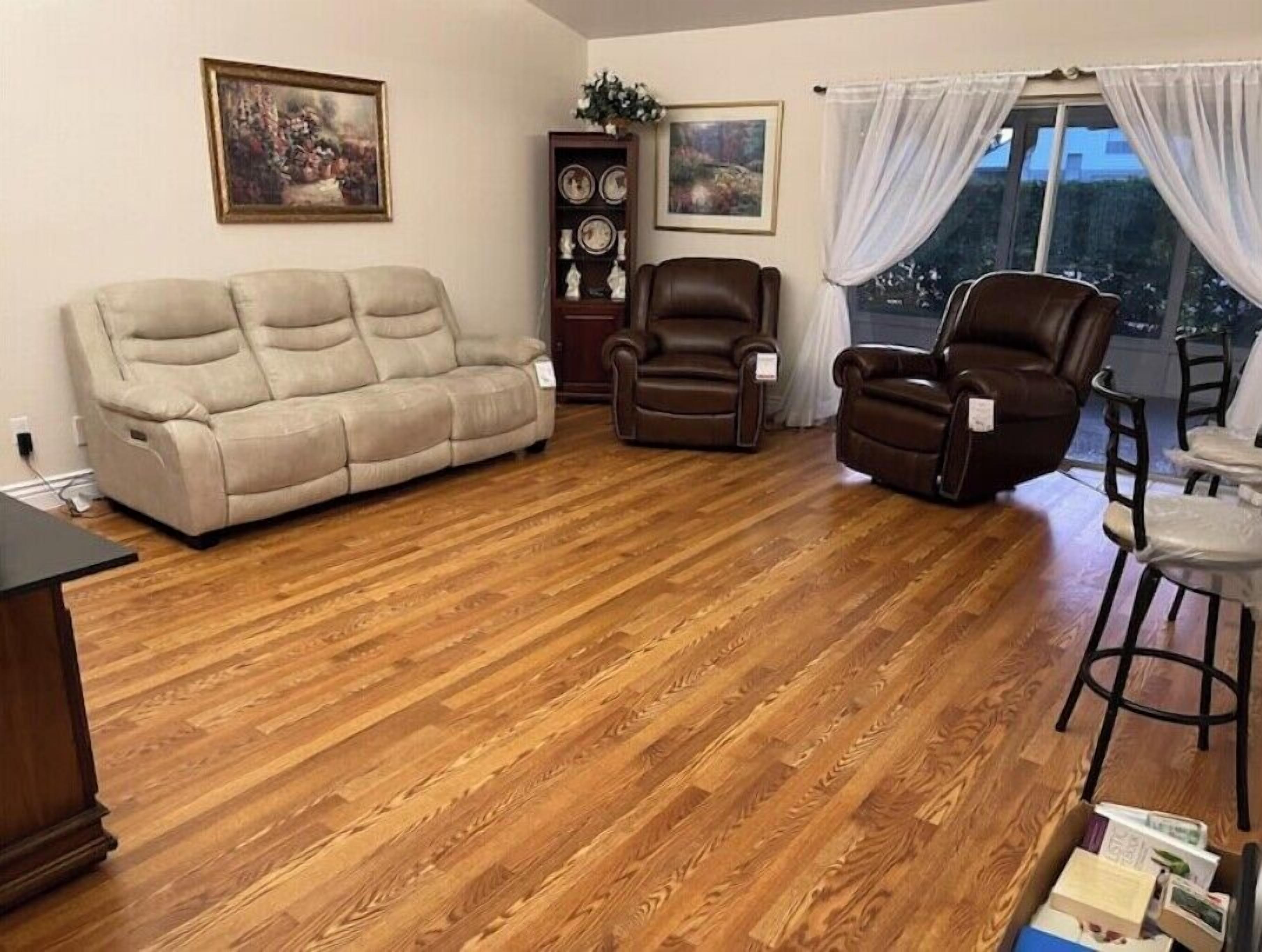 Un salon avec un canapé beige, deux fauteuils en cuir marron, une table basse en bois et un coin repas comprenant une petite table et des chaises.
