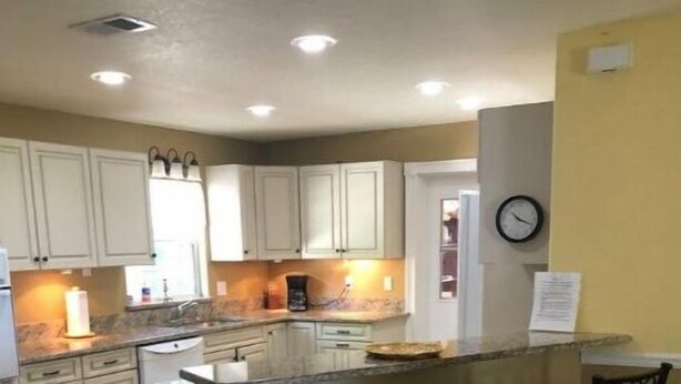 A kitchen with a central island, two bar stools, and a clock on the wall. - Cisky Park Leesburg over looking Lake Harris (Leesburg)