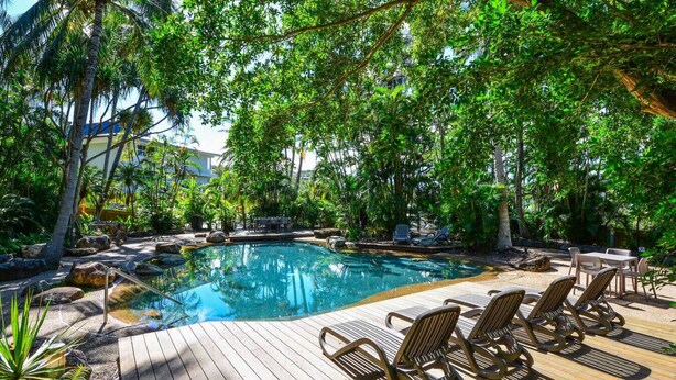 A pool area with lounge chairs and a wooden deck. - Poinciana 012 Hamilton Island & Buggy (Whitsundays)