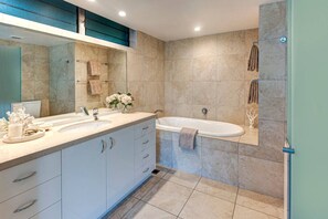 A modern bathroom with a double sink vanity, a freestanding bathtub, and a large mirror.