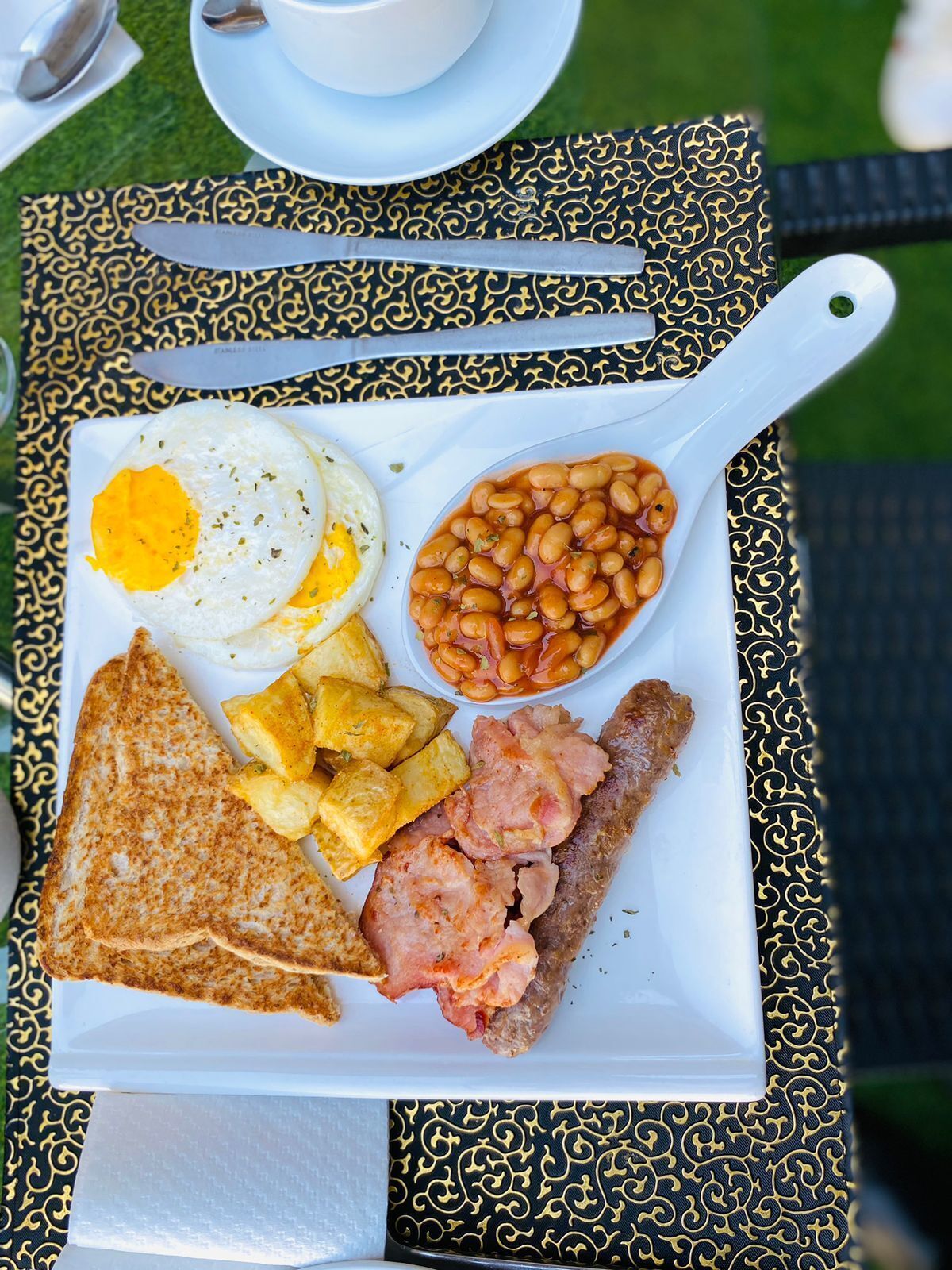 A breakfast plate with eggs, beans, toast, hash browns, and sausage.