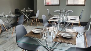 Een eetgedeelte met glazen tafels en stoelen, klaar voor een maaltijd.