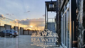 Un albergue boutique con un cartel que dice "SEA WATER BOUTIQUE LODGE" y una botella de whisky sobre una mesa.