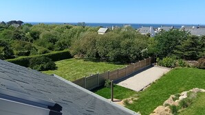 Un área residencial con vista al mar, un patio cercado y casas al fondo.