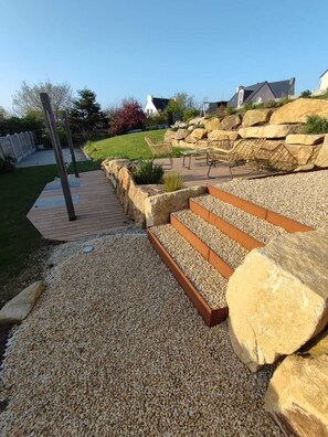A garden area with a wooden deck, stone planters, and outdoor furniture. - House with a garden, 500 meters from the beach (Plouarzel)