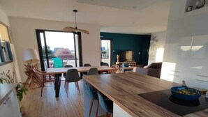 Una cocina moderna con una isla de madera, armarios blancos y un comedor con sillas y una mesa.