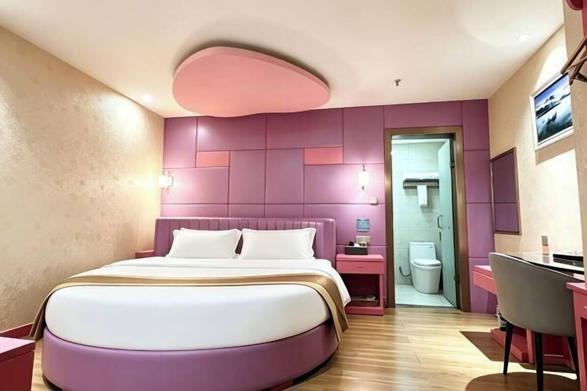A modern hotel room with a large bed, bedside tables, a desk, and a chair.