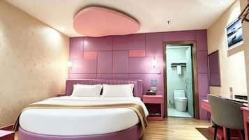 A modern hotel room with a large bed, bedside tables, a desk, and a chair.