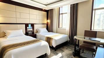 A hotel room with two beds, a desk, and a chair.