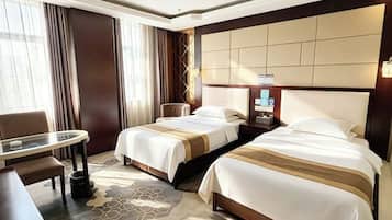 A hotel room with two beds, a desk, a chair, and a large window with curtains.