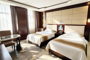 A hotel room with two beds, a desk, a chair, and a large window with curtains. - Jinrun Holiday Hotel (Korla)
