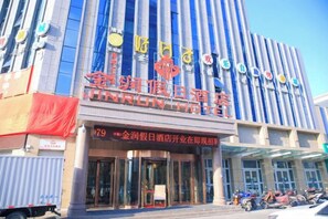 Un hotel con fachada moderna, amplios ventanales y una entrada destacada con señalización.