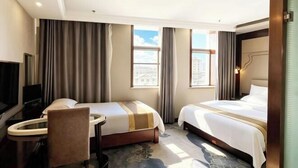 A hotel room with two beds, a desk, a chair, a television, and large windows. - Jinrun Holiday Hotel (Korla)