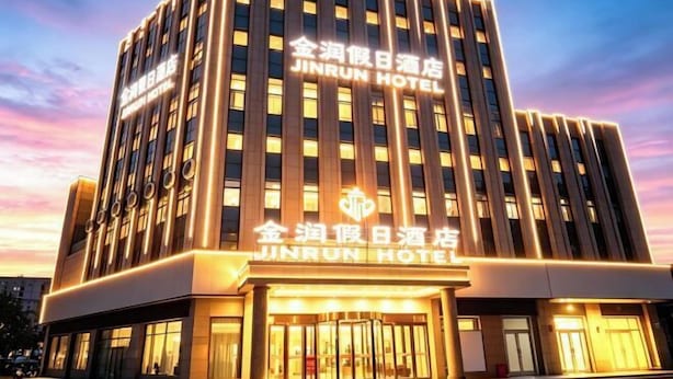 A multi-story hotel with a prominent sign reading 'JINRUN HOTEL'. - Jinrun Holiday Hotel (Korla)