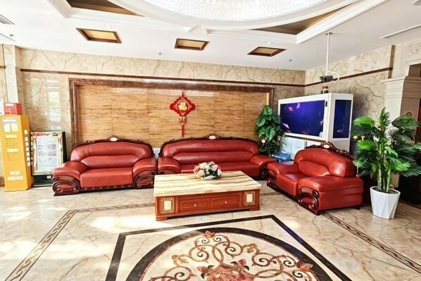 A lobby with leather sofas, a coffee table, a TV, and a potted plant.