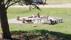A rustic outdoor seating area with a bench, logs, and a fire pit. - View of Lake Granby - LOCATION (Grand Lake)