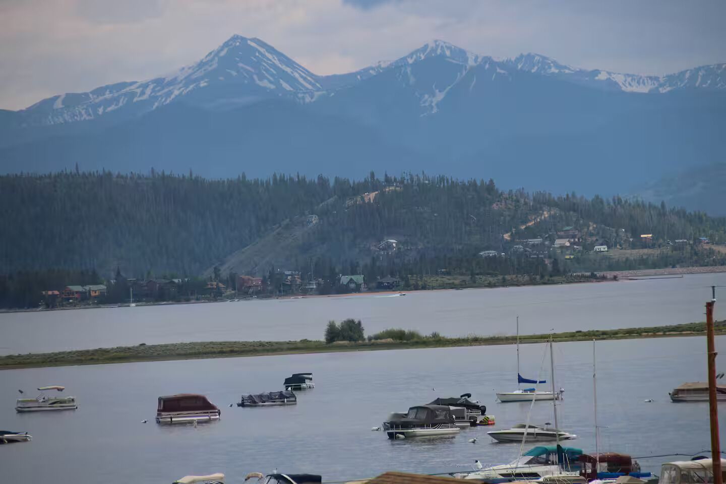 Un lac avec des bateaux et une chaîne de montagnes en arrière-plan.