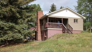 A two-story log cabin with a balcony, surrounded by trees. - View of Lake Granby - LOCATION (Grand Lake)