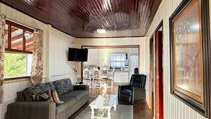 A living room with a sofa, a coffee table, a chair, and a television. - Casa Aconchegante na Lagoa de Ibiraquera (Imbituba)