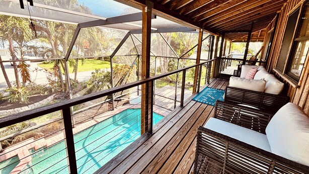 Une terrasse en bois avec une piscine, un espace salon extérieur et une vue sur la végétation environnante.