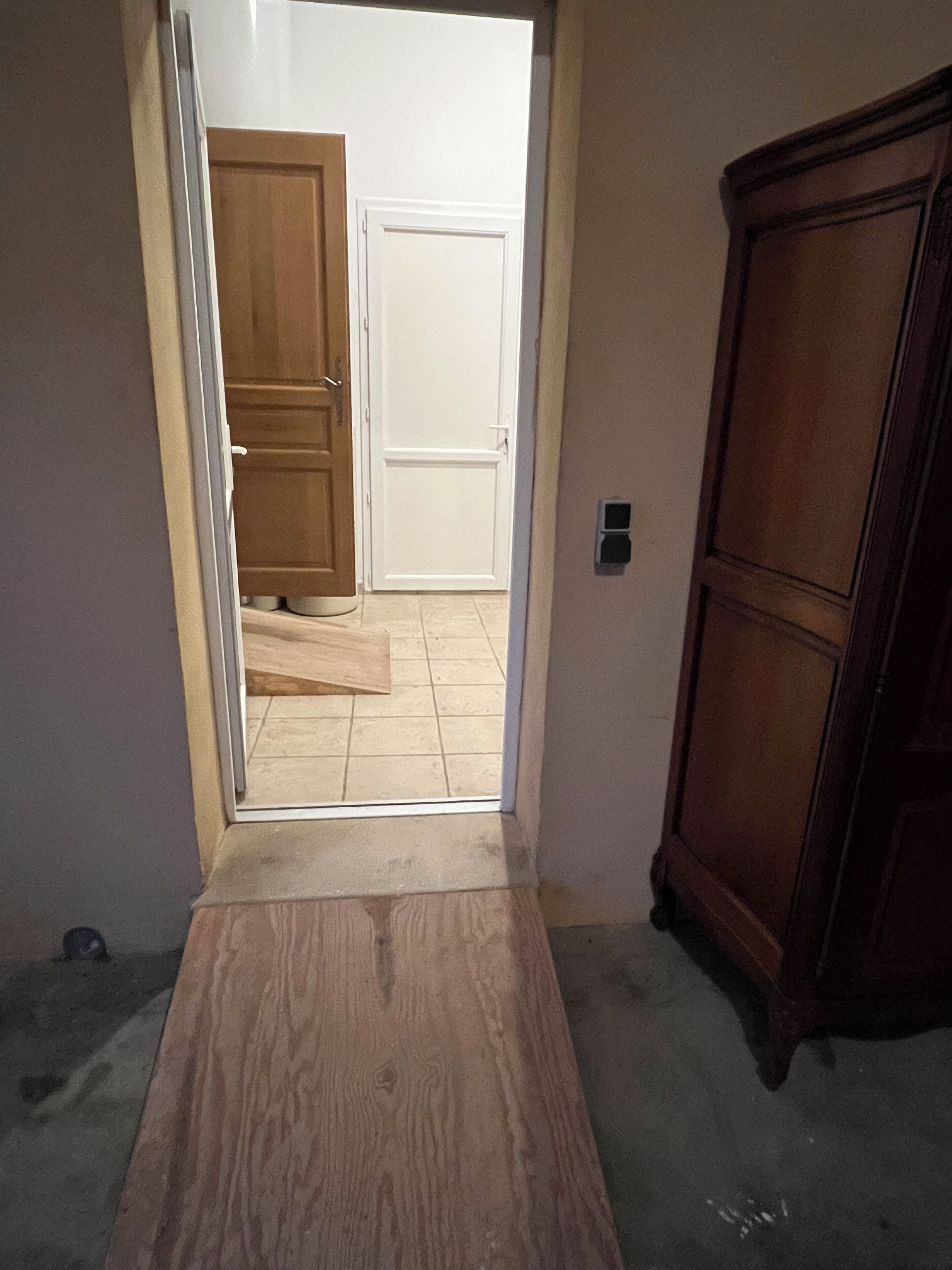 A hallway with a wooden floor, a cabinet, and a door leading to another room.