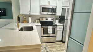 A modern kitchen with white cabinets, stainless steel appliances, and a grey refrigerator. - Work & Family Travel Friendly-Pool, Marina, Golf with Fee (Niceville)