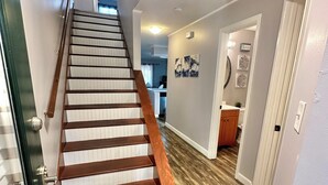 A staircase with wooden steps and a handrail, leading to a room with a kitchen area visible in the background. - Work & Family Travel Friendly-Pool, Marina, Golf with Fee (Niceville)