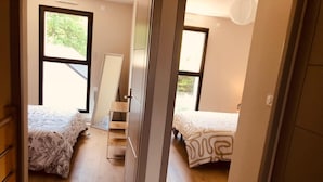 Une chambre avec deux lits, un plancher en bois et une fenêtre.