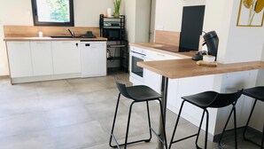 Une cuisine moderne avec des meubles blancs, un plan de travail en bois et des tabourets de bar noirs.
