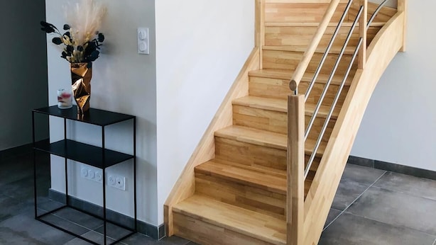 Un escalier moderne avec des marches en bois et des rampes en métal, menant à l’étage supérieur.